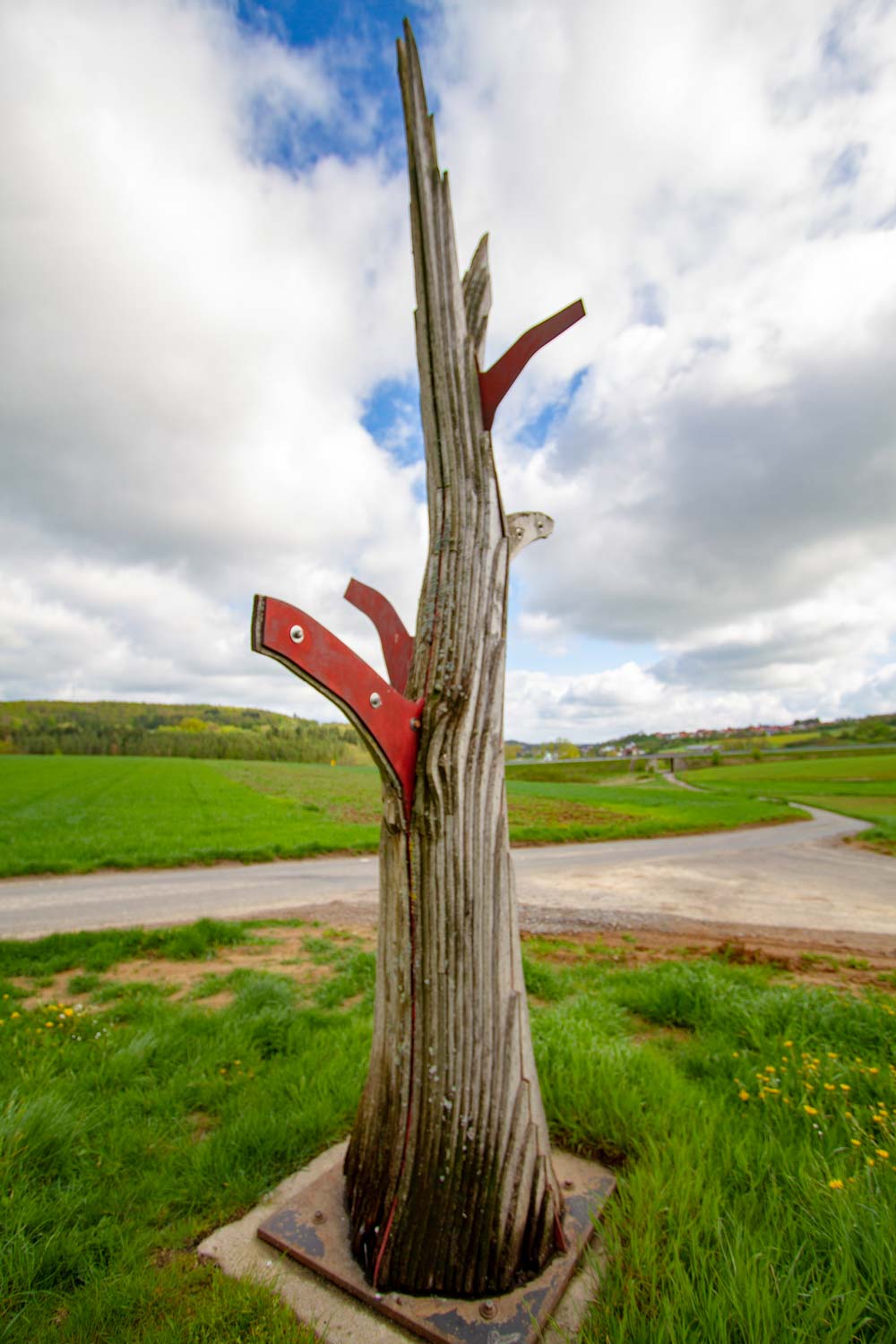 Baumskulptur mit roten und braunen Brettern